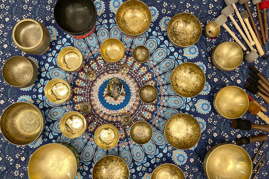Singing bowls, tingsha and mallets laid out on a mandala cloth