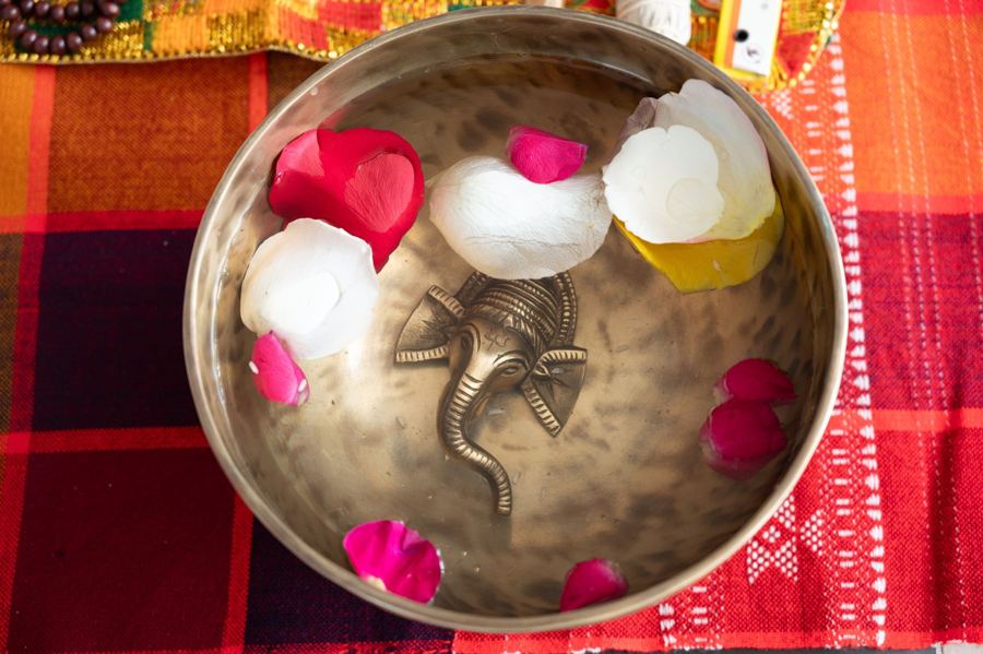 A singing bowl with a brass Ganesha, water and rose petals
